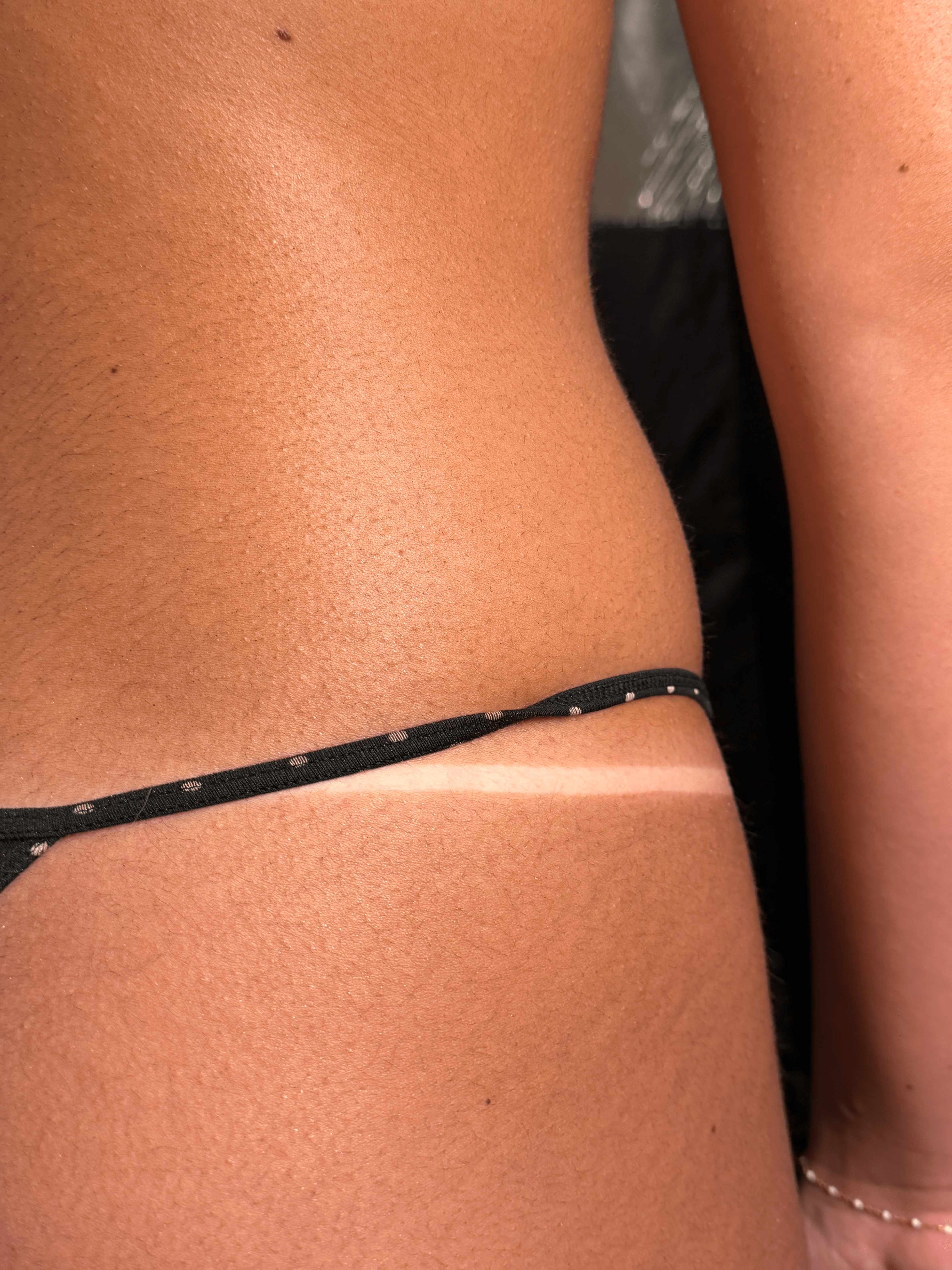 Rich, dark brown spray tan on the hip and waist with a crisp, clean bikini tan line