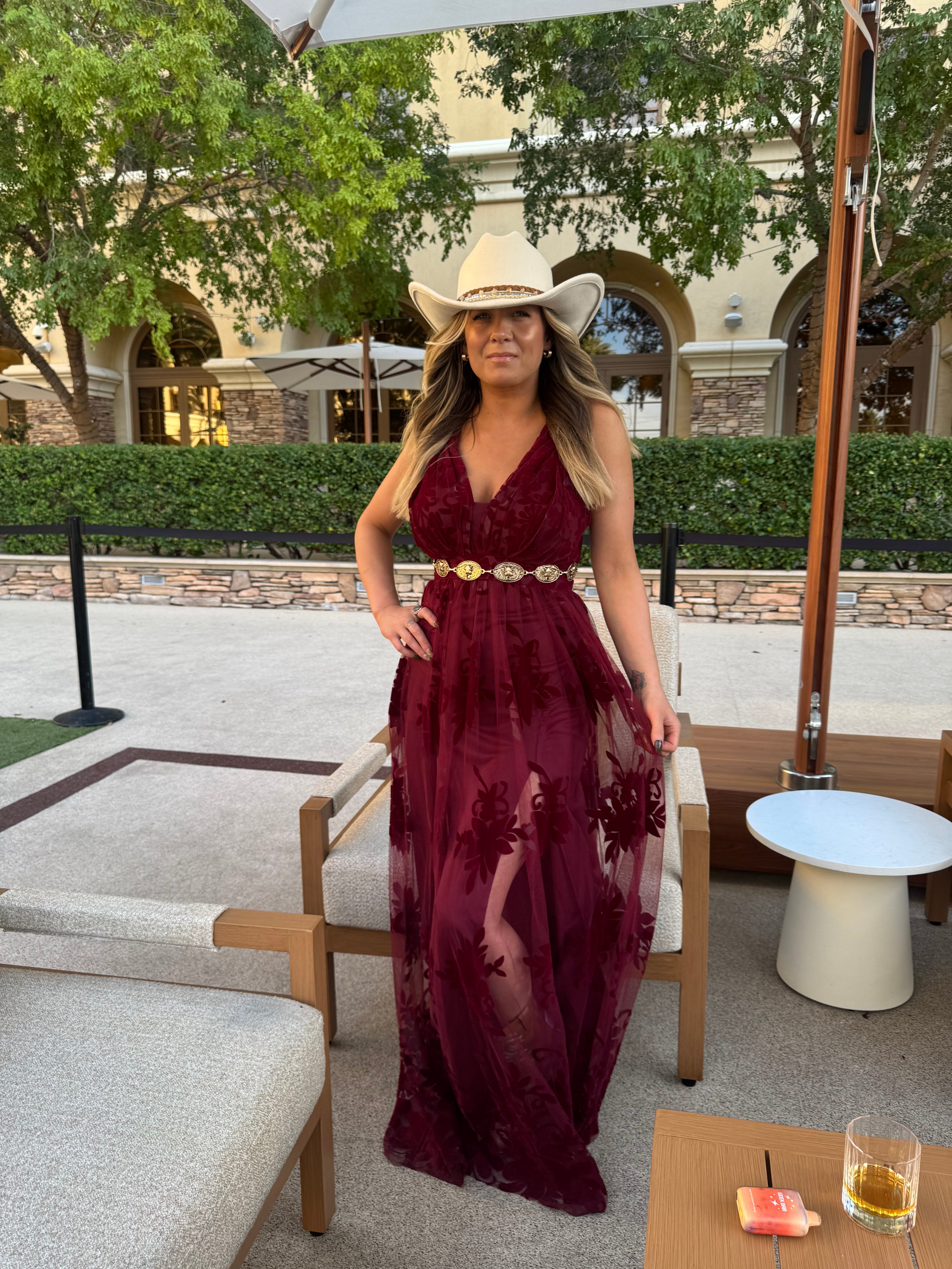Client in a burgundy velvet maxi dress and white cowboy hat showing off a warm, natural sun-kissed glow