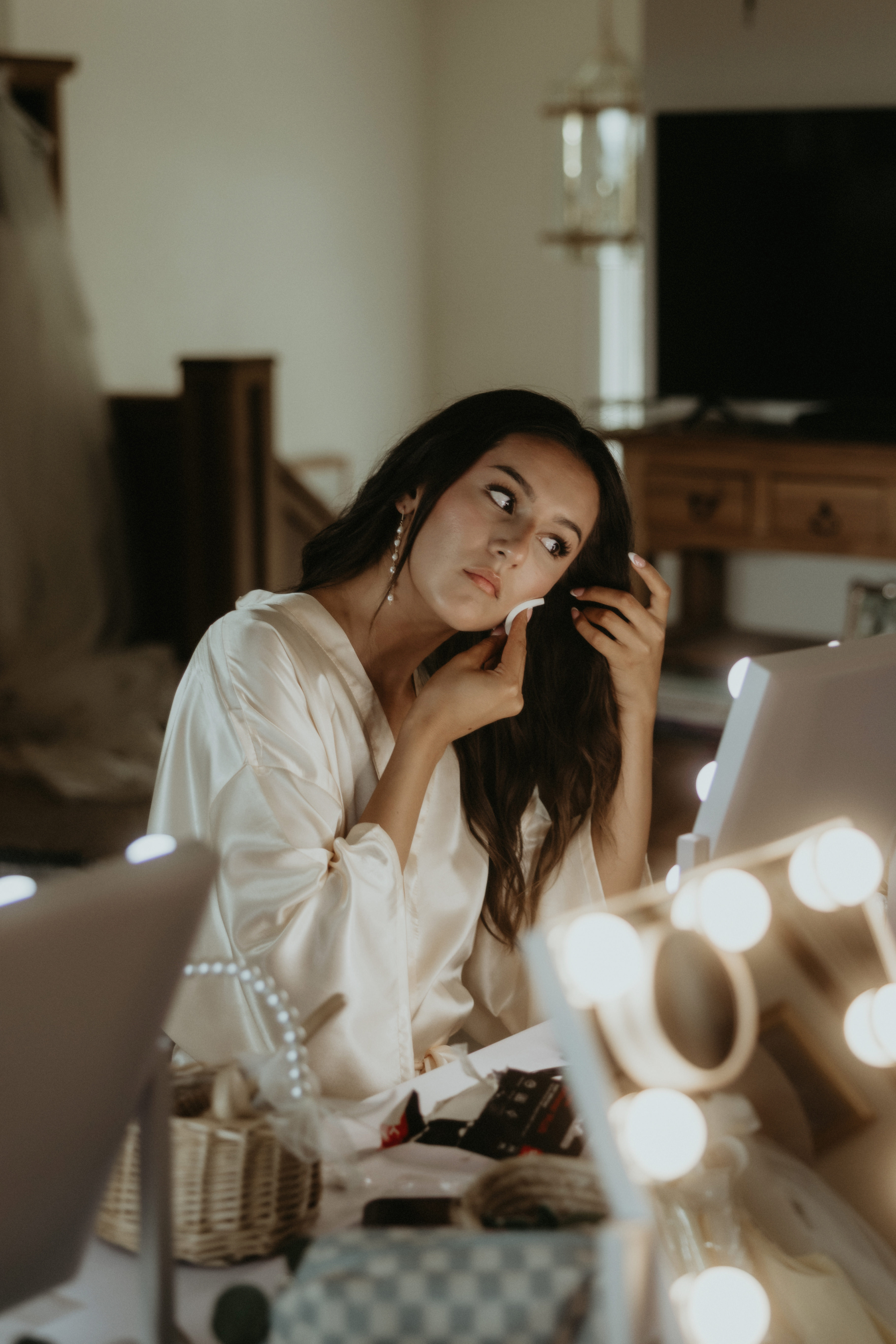 Client getting glam-ready at a lit vanity with a flawless sun-kissed glow